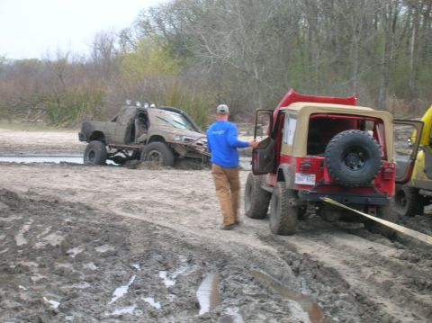 1996 Ford Bronco - A red Jeep Wrangler is being towed by a yellow vehicle while a muddy truck remains stuck in the background at Marlin City Lake.