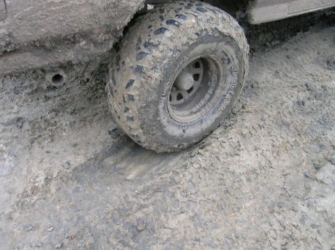 1996 Ford Bronco - A vehicle's tire is stuck in thick mud, with the fender also covered in dirt.