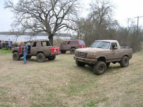1996 Ford Bronco - A muddy 1992 Ford Bronco is parked in a grassy field with other off-road vehicles.