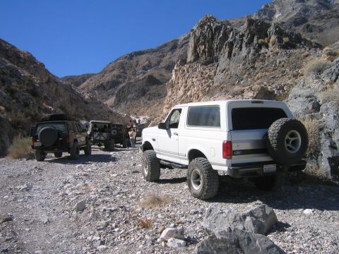1993 Ford Bronco - White 1993 Ford Bronco navigates a rough, rocky terrain in a mountainous area.