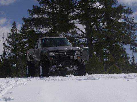 1986 Ford Bronco - Modified pickup truck with off-road tires navigates a snowy landscape.
