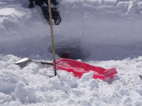 1986 Ford Bronco - A red sled and shovels are visible in the snow near a hole, suggesting activity in a winter environment.