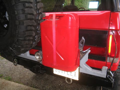 1989 Ford Bronco - The rear of a red SUV shows a spare tire, a red gas can mounted on the bumper, and a custom rear bumper.