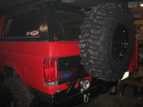 1989 Ford Bronco - Rear view of a red 1989 Ford Bronco a large spare tire mounted on a custom rear bumper.