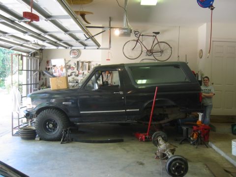 1995 Ford Bronco - A black Ford Bronco is undergoing maintenance in a garage, with its rear axle detached.