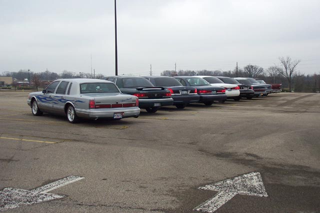 Rear view of flamed silver Lincoln Town Car ahead of a row of parked sedans