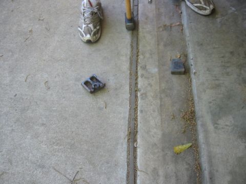 1995 Ford Bronco - A metal bracket lies on the ground near a hammer, suggesting a repair or modification is underway.