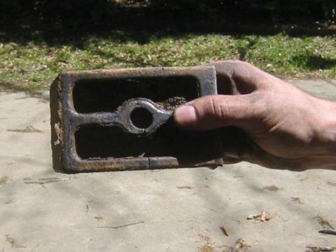 1995 Ford Bronco - A hand holds a worn metal part, possibly a component from a vehicle's suspension or chassis.