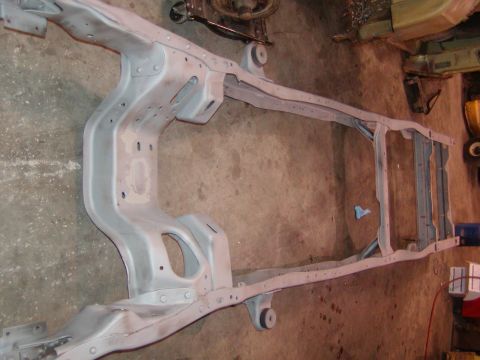 1991 Ford Bronco - A vehicle frame, likely from an older model, is shown on a workshop floor, ready for restoration.