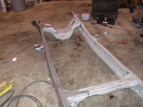 1991 Ford Bronco - A bare vehicle frame rests on a concrete floor, surrounded by tools and tires.