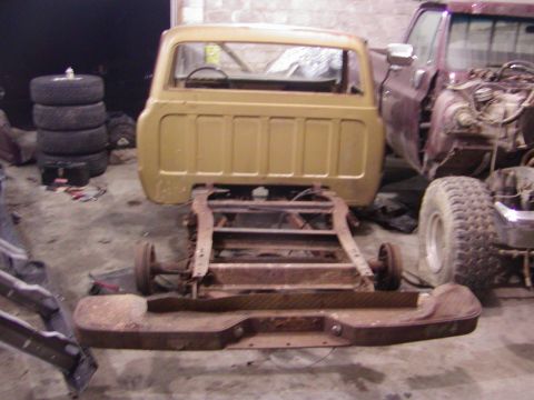 1991 Ford Bronco - A disassembled pickup truck sits in a garage next to another vehicle.