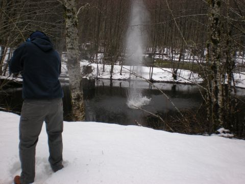 1993 Ford Bronco - A person stands by a river in a snowy landscape, with water spraying upwards.