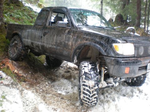 1993 Ford Bronco - This heavily modified Toyota Tacoma is navigating a challenging off-road course covered in snow and mud.