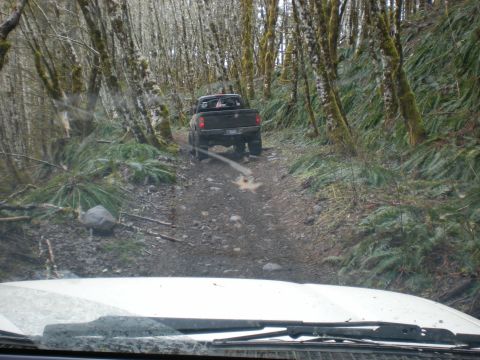 1993 Ford Bronco - Two vehicles on a wooded trail, one following the other on a muddy path.