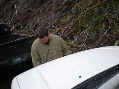 1993 Ford Bronco - A man inspects the hood of a white vehicle parked next to a black pickup truck.