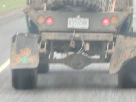 1993 Ford Bronco - The rear view of a dirty truck shows its dual rear wheels and a spare tire, with a license plate mounted centrally.