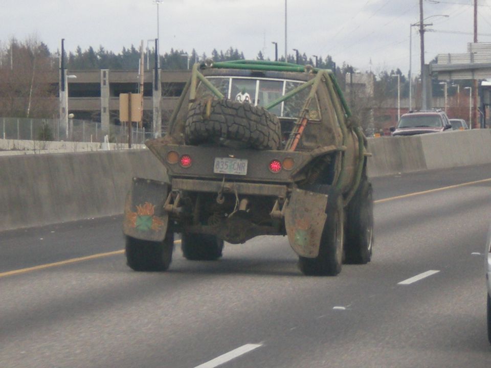 Rear view of a heavily modified truck with a roll cage and spare tire