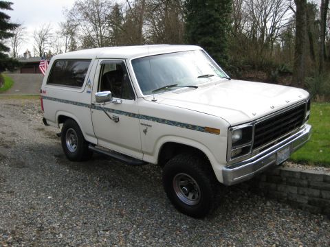1980 Ford Bronco - A white 1980 Ford Bronco is parked on a gravel driveway with trees in the background.