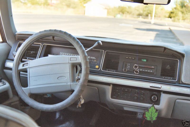 Gray dashboard and steering wheel of a 1991 Ford Crown Victoria, showing the radio and climate controls