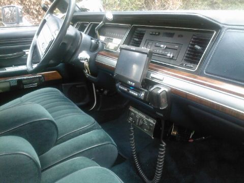 1991 Ford Crown Victoria - The interior of a 1991 Ford Crown Victoria features teal velour seats, a wood-grain dashboard, and an aftermarket radio installation.