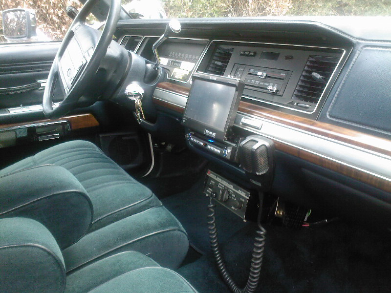 Teal velour interior of a 1991 Ford Crown Victoria with wood-grain trim and aftermarket radio