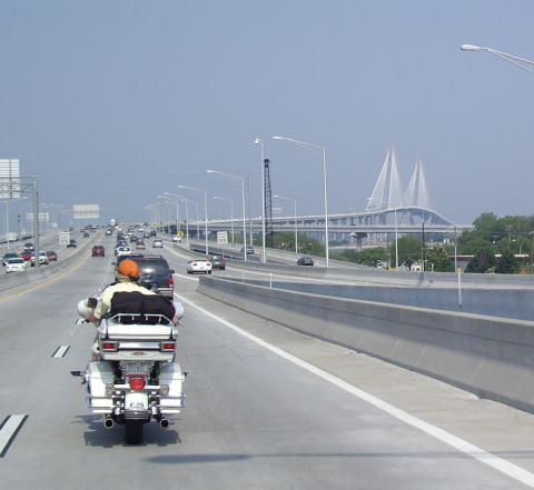 2005 BMW R1200CA ABS - A motorcycle with two riders travels on a highway with a large bridge in the background.
