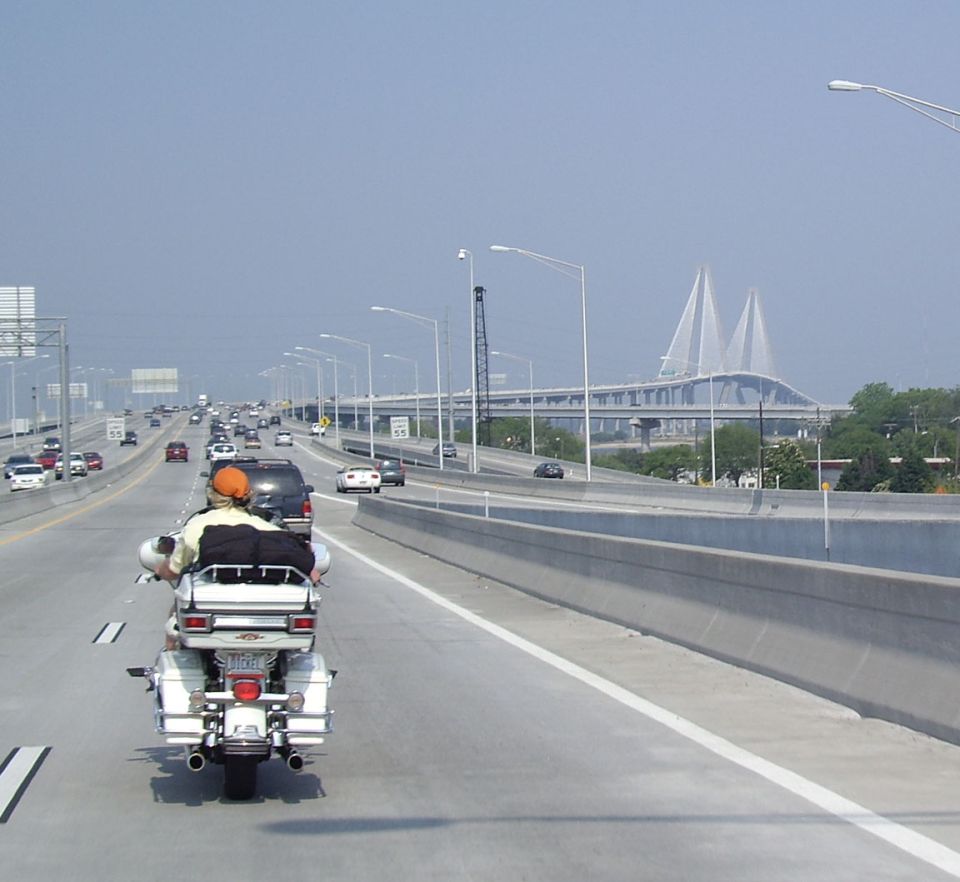 White motorcycle with two riders on a highway, rear view