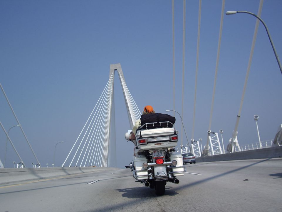 Rear view of a white motorcycle on a bridge with a rider