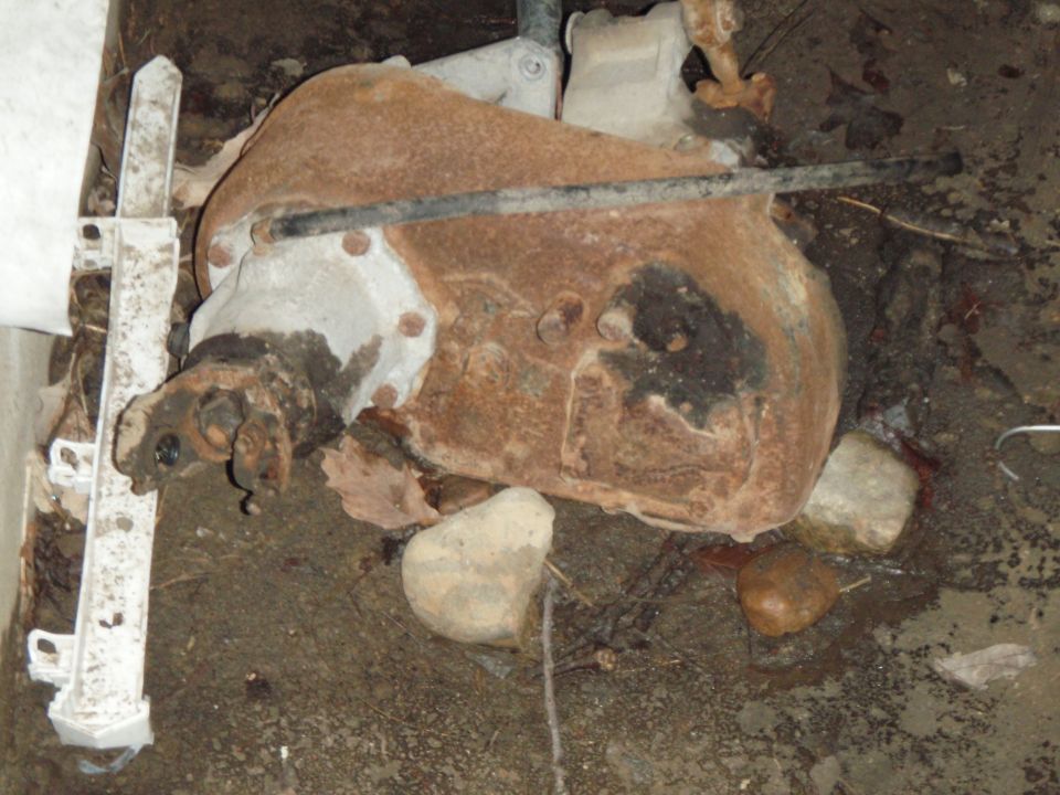 Rusty cast-iron differential housing lying on dirt ground