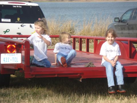 1989 Ford Bronco II - Three girls sit on a trailer near a lake, with two SUVs visible in the background.