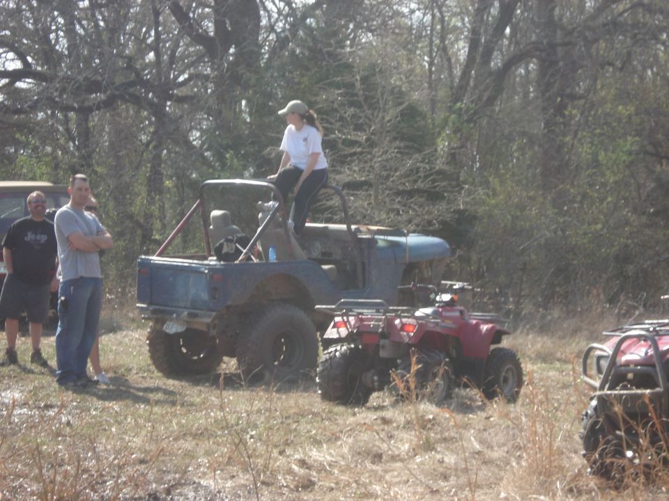 Off-road vehicles and people gathered in a wooded area