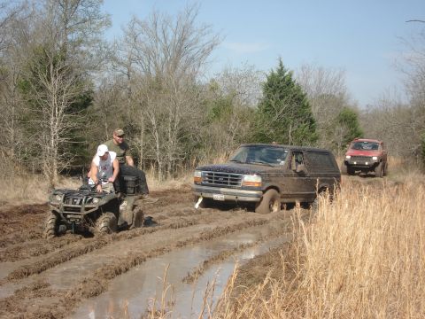 1989 Ford Bronco II - Two vehicles navigate a muddy trail; one ATV and two SUVs are visible.