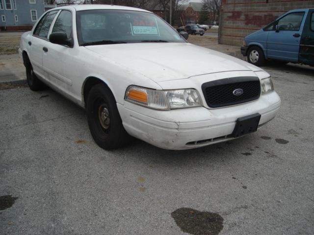 White Ford Crown Victoria parked on asphalt. A 'For Sale' sign is on the windshield