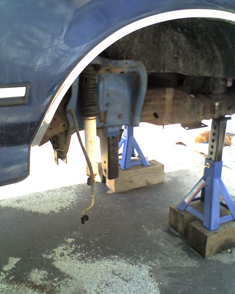 1996 Ford F-150 - The vehicle's front suspension is disassembled and supported by jack stands for maintenance.