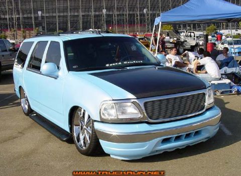2000 Ford Expedition - This light blue SUV features a contrasting black hood and a modified grille, seen from a 3/4 front angle.