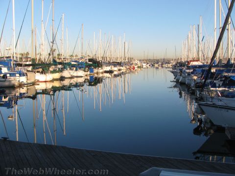 1990 Ford Bronco - quiet marina at dawn with rows of moored sailboats and their masts mirrored in calm, glassy water.