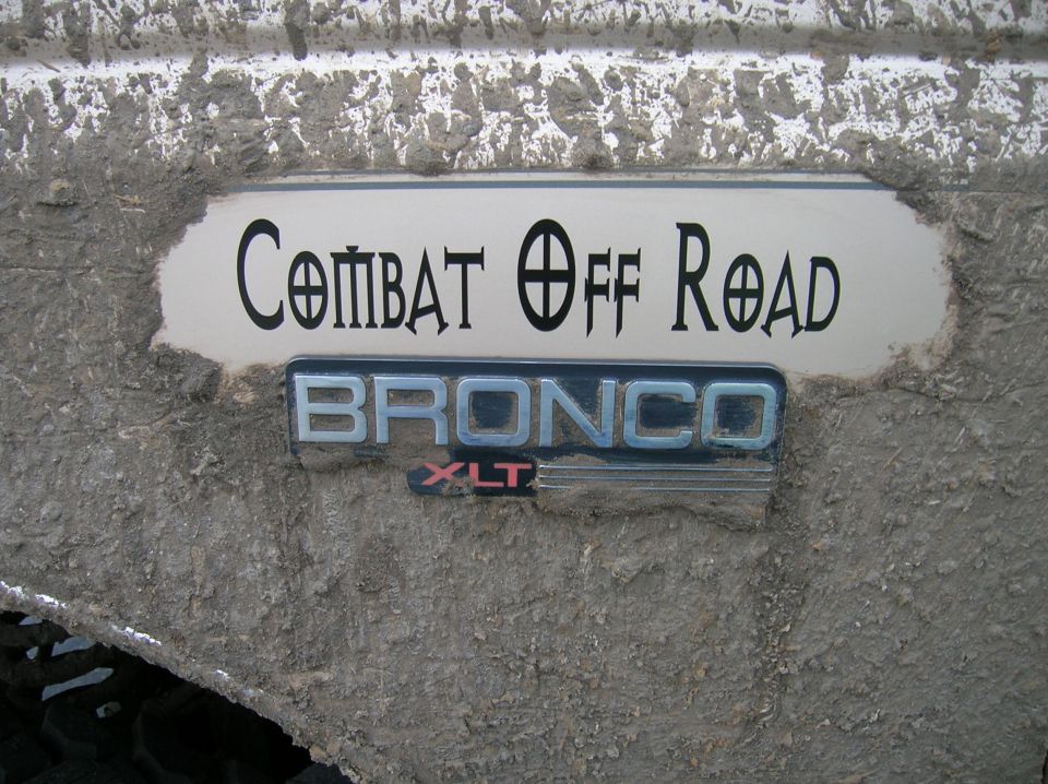 Mud-caked white panel with chrome BRONCO XLT emblem and off-road decal