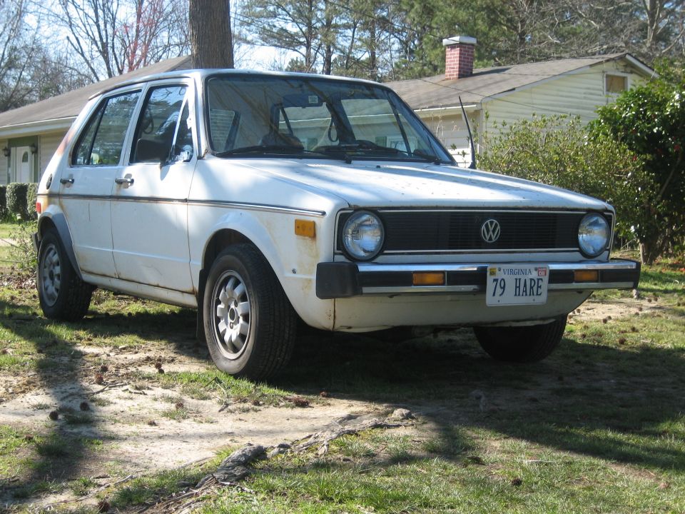 White VW Rabbit Mk1 hatchback, front 3/4 view, rusty, parked on grass