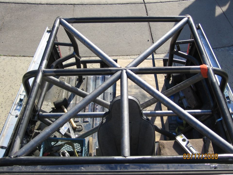 Roll cage structure inside a truck bed with a seat and tools visible