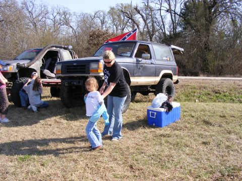 1981 Jeep CJ7 - A dark blue Ford Bronco II flies a Confederate flag while parked in a grassy field next to another off-road vehicle.