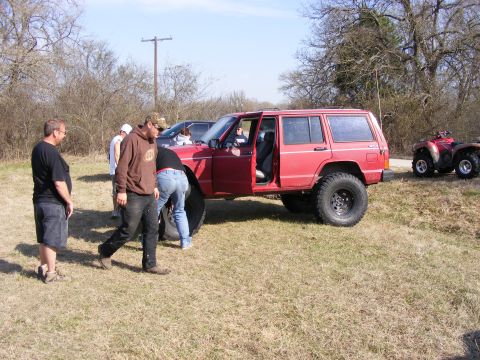 1981 Jeep CJ7 - A red Jeep Cherokee XJ is parked on a grassy field with several people gathered around it.
