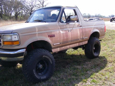 1981 Jeep CJ7 - This Ford Bronco is lifted and has large off-road tires. A second vehicle is in the distance.