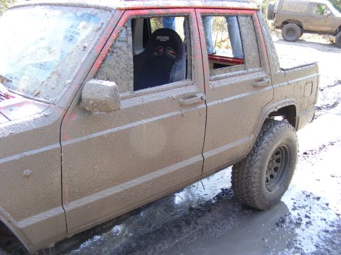 1981 Jeep CJ7 - This mud-covered Jeep Cherokee XJ is seen off-road, with another Jeep visible in the background.