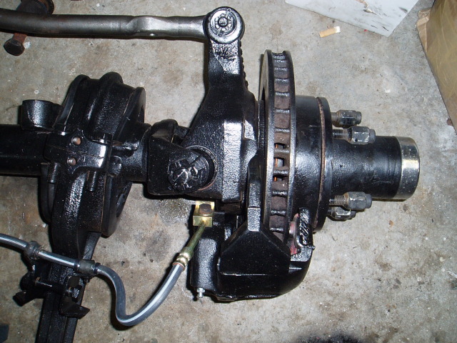 Removed front drive axle and steering knuckle assembly on a garage floor