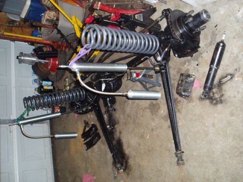 1980 Ford Bronco - Various automotive suspension components are disassembled and arranged on the ground.