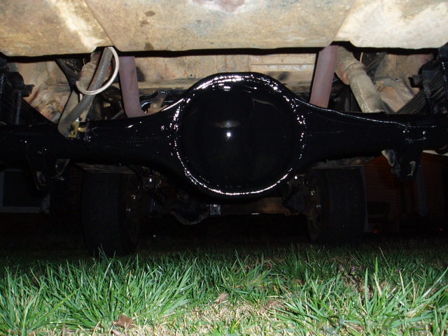 Underside view of a black rear differential and suspension components with exhaust pipes