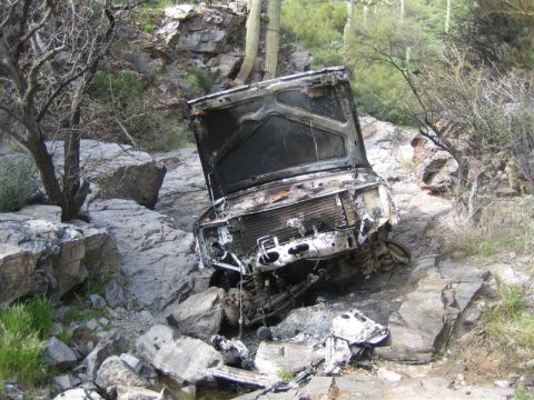 1987 Suzuki Samurai - A severely damaged vehicle sits wrecked in a rocky, desert-like environment.