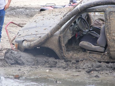 1981 Jeep CJ7 - An off-road vehicle is deeply stuck in mud, with a snorkel extending from the hood.