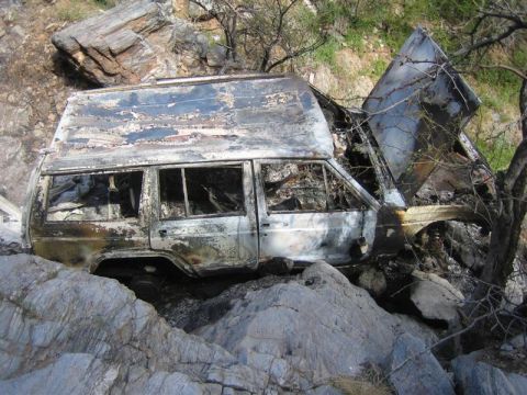 1987 Suzuki Samurai - A heavily damaged and burned SUV is lodged precariously among rocks and trees.