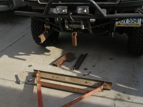 1990 Ford Bronco - Parts for a tow bar project are laid out on the ground in front of a vehicle's bumper and winch.